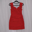 Red mini dress on a hanger against a white curtain background