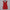 Red mini dress on a hanger against a white curtain background