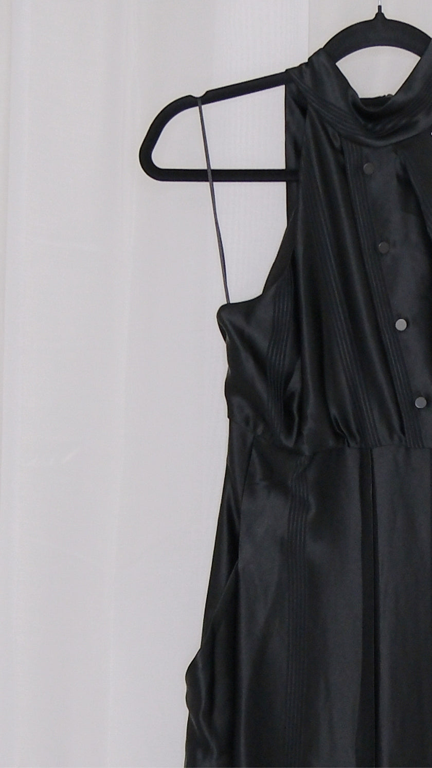 Black satin jumpsuit on a hanger against a white background