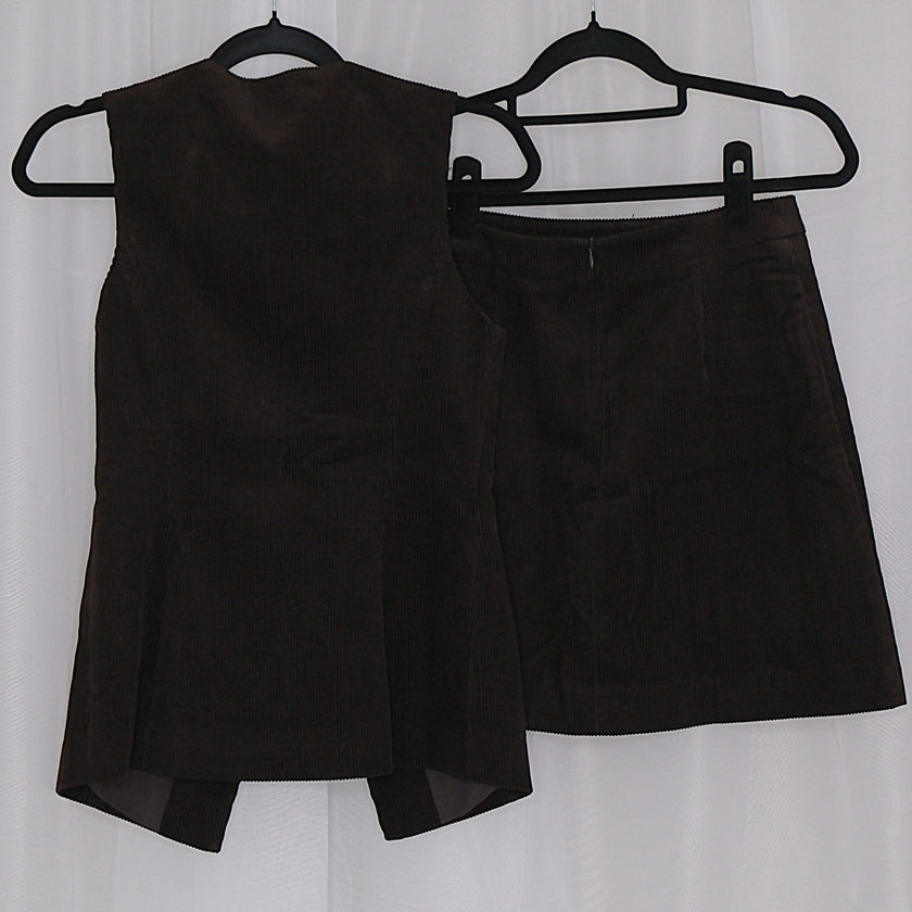 Chocolate corduroy vest and skirt set on hangers against a white background