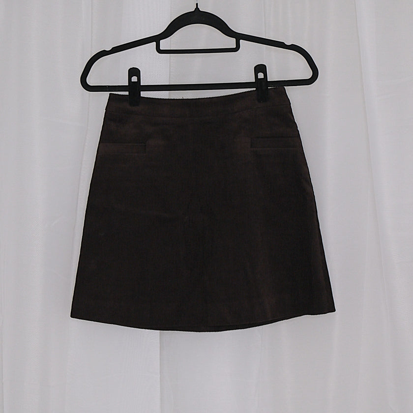 Chocolate corduroy vest and skirt set on hangers against a white background