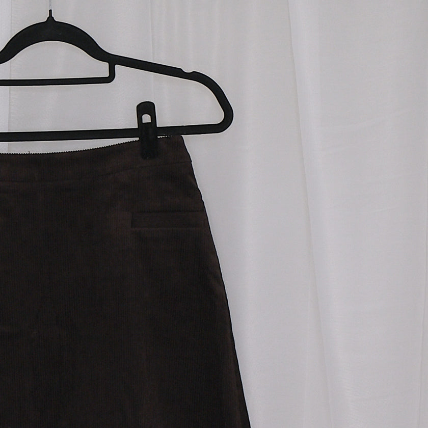 Chocolate corduroy vest and skirt set on hangers against a white background