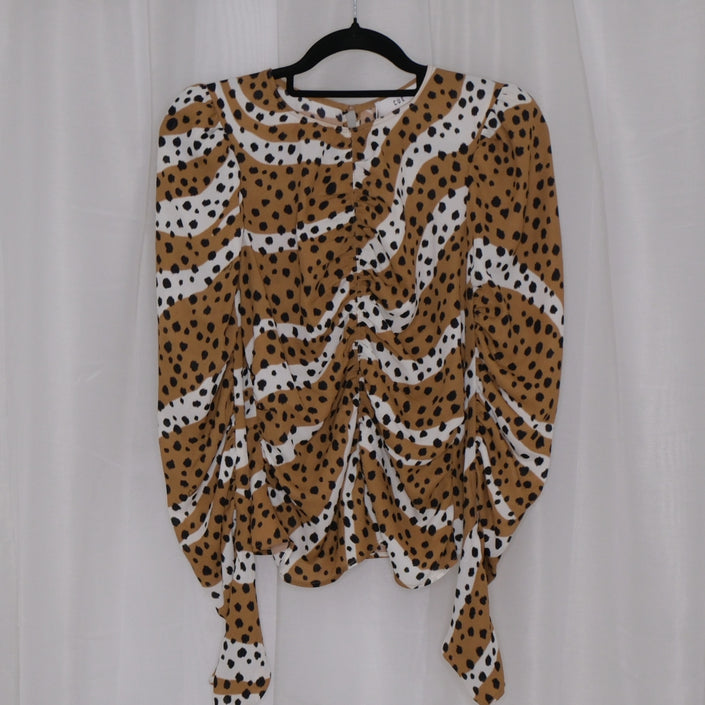 Leopard print top on a hanger against a plain background