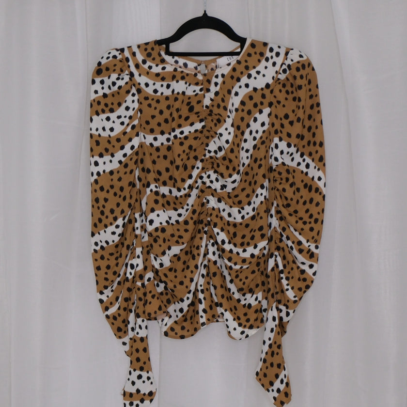 Leopard print top on a hanger against a plain background