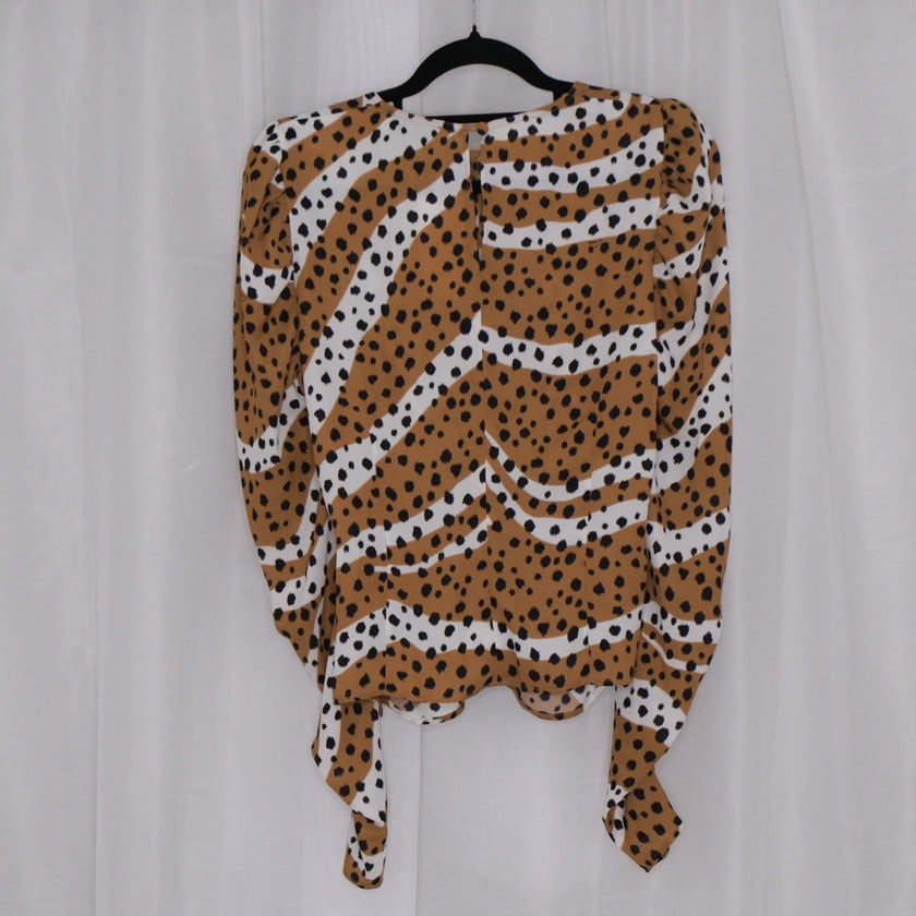 Leopard print top on a hanger against a plain background