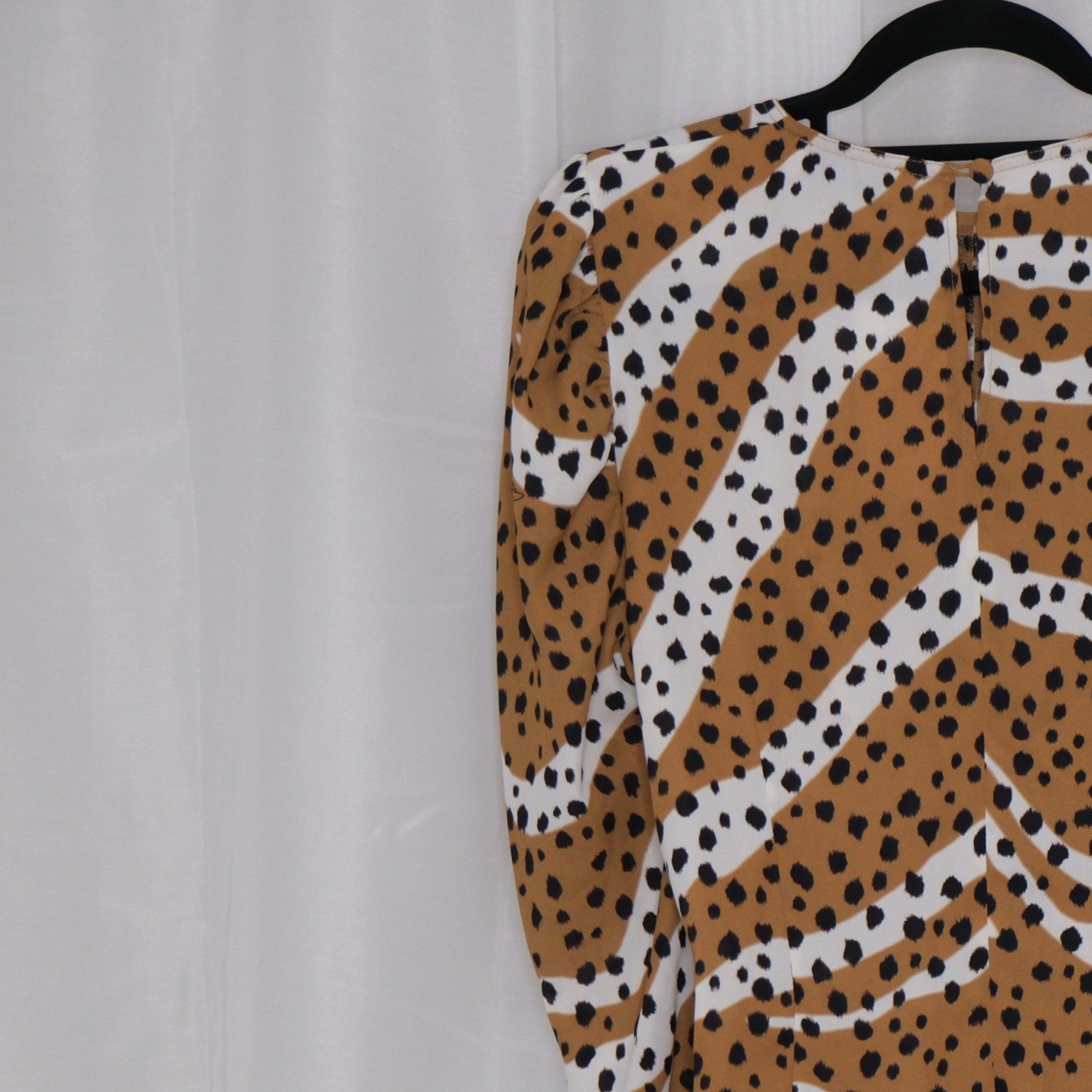 Leopard print top on a hanger against a plain background