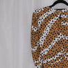 Leopard print top on a hanger against a plain background