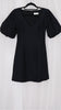 Black mini dress with puff sleeves on a hanger against a white background