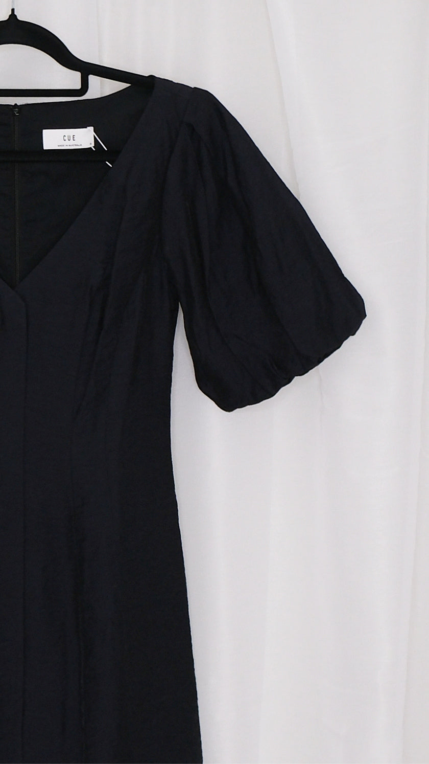 Black mini dress with puff sleeves on a hanger against a white background