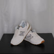 White sneakers with grey leopard design on a black surface and white sheer curtain background

