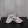 White sneakers with grey leopard design on a black surface and white sheer curtain background

