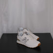 White sneakers with grey leopard design on a black surface and white sheer curtain background