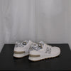 White sneakers with grey leopard design on a black surface and white sheer curtain background
