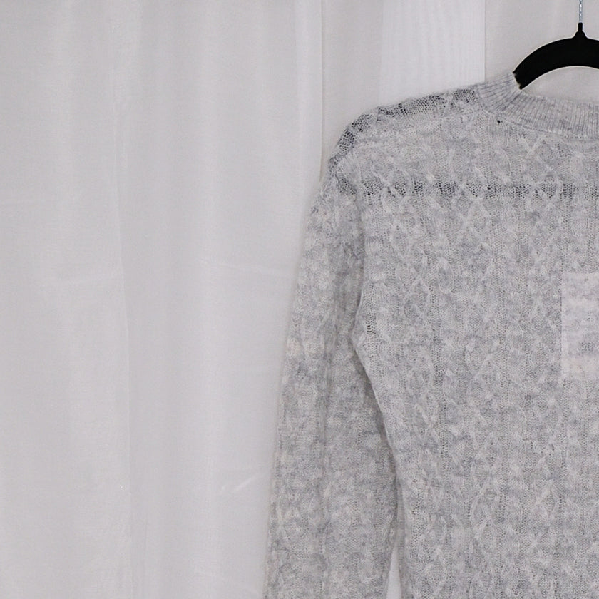 Grey sweater on a hanger against a white background