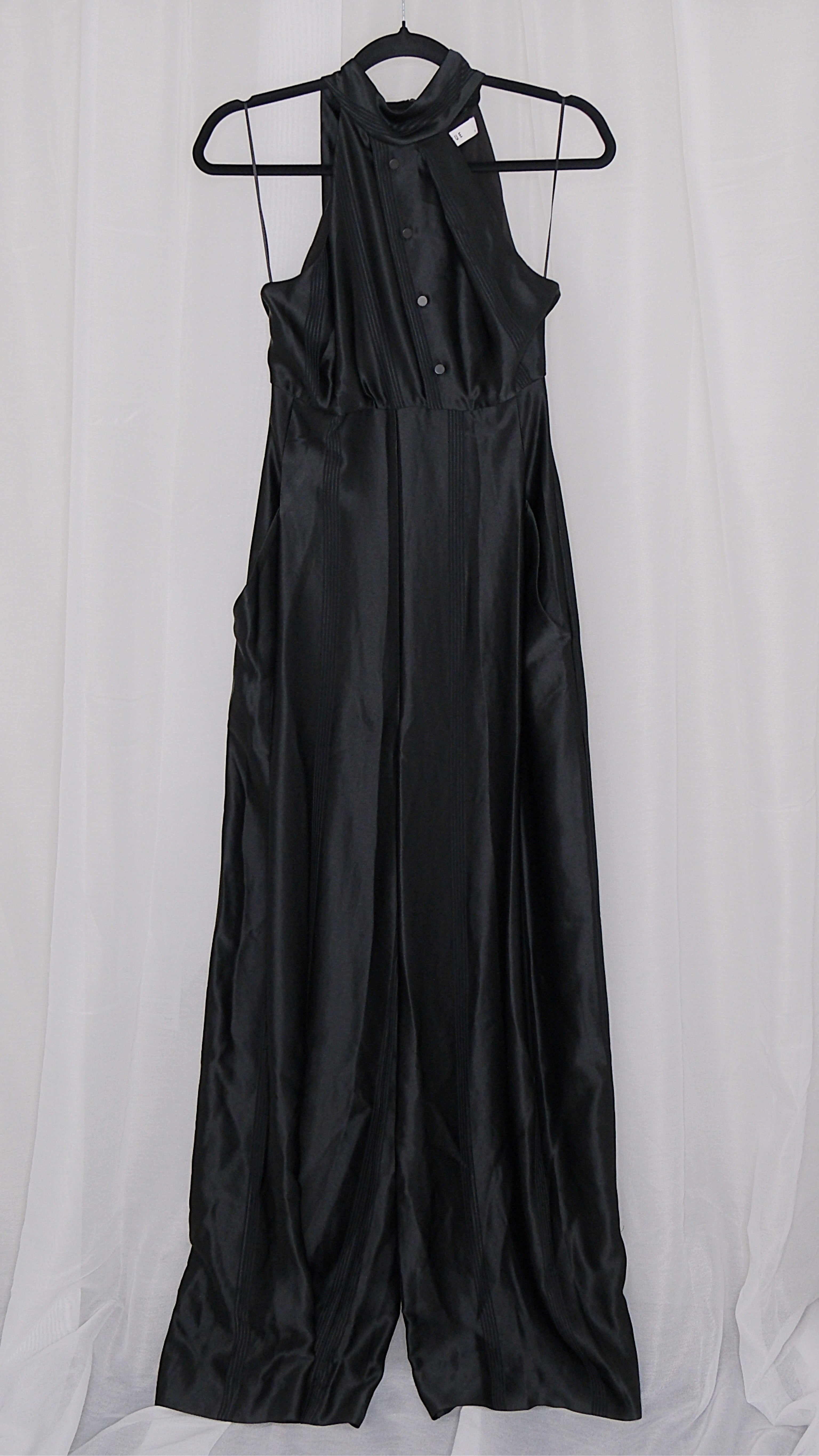 Black satin jumpsuit on a hanger against a white background