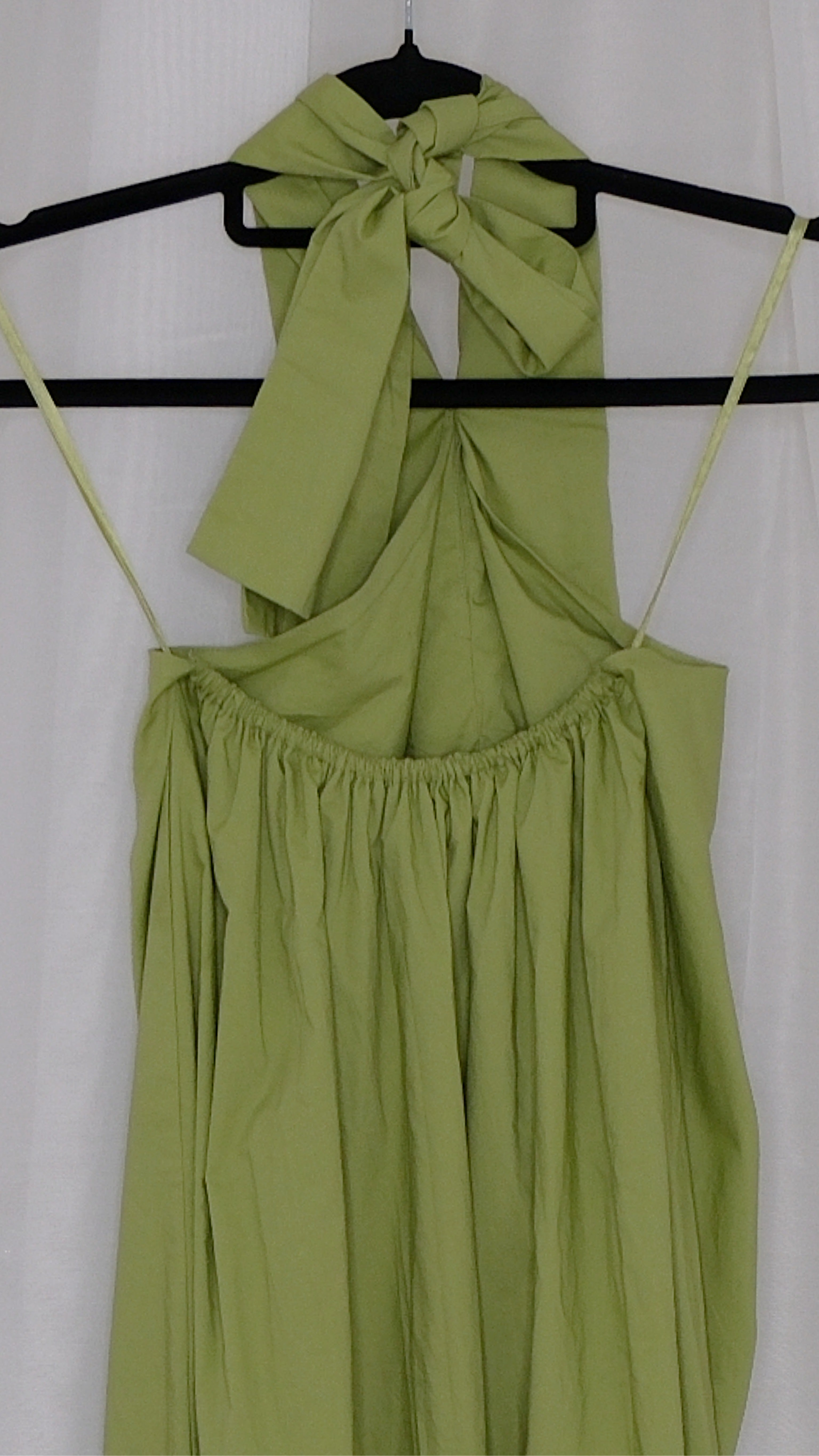 Green halter neck dress on a hanger against a white background