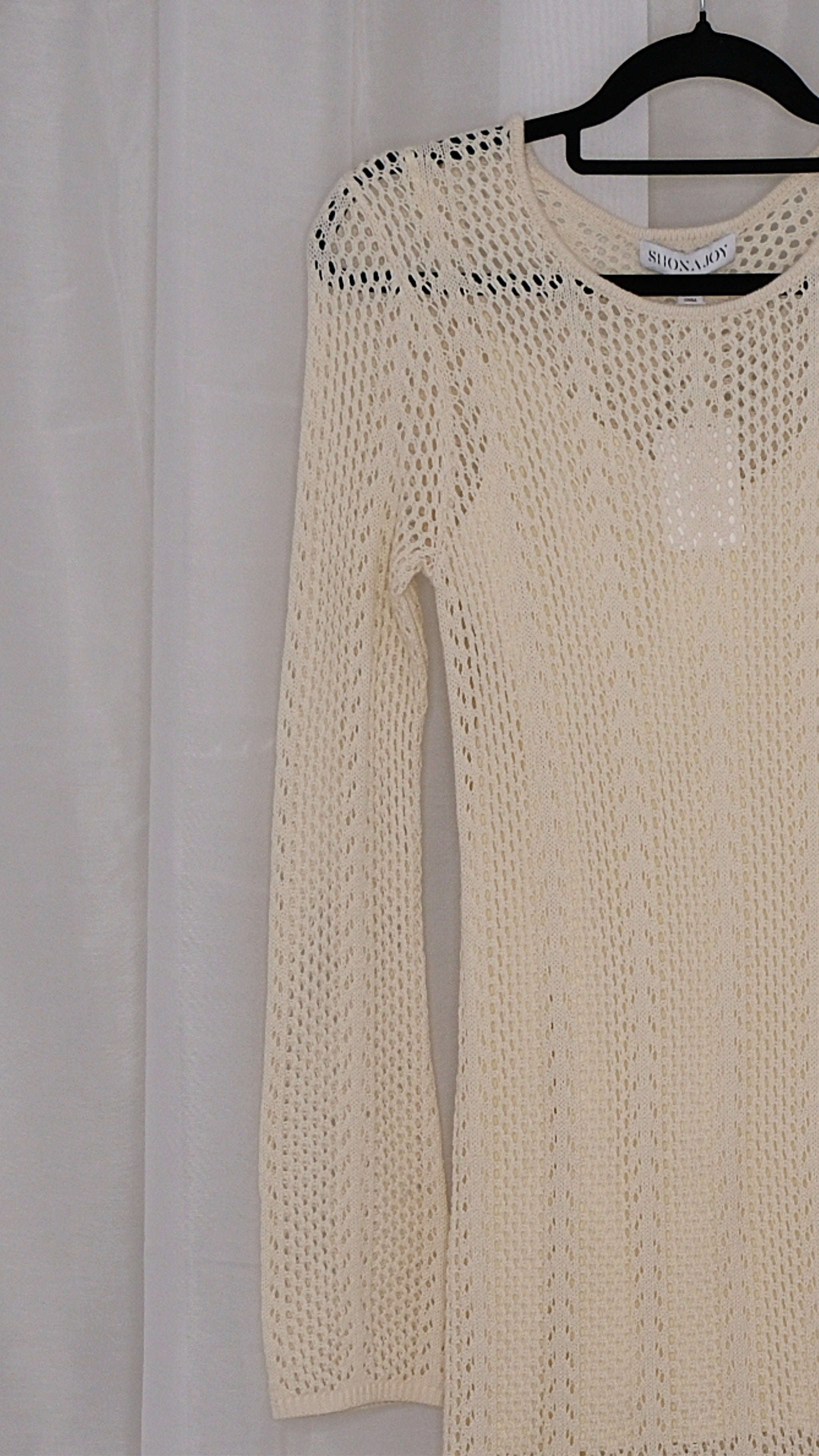 Beige long-sleeve crochet dress on a hanger against a light white background