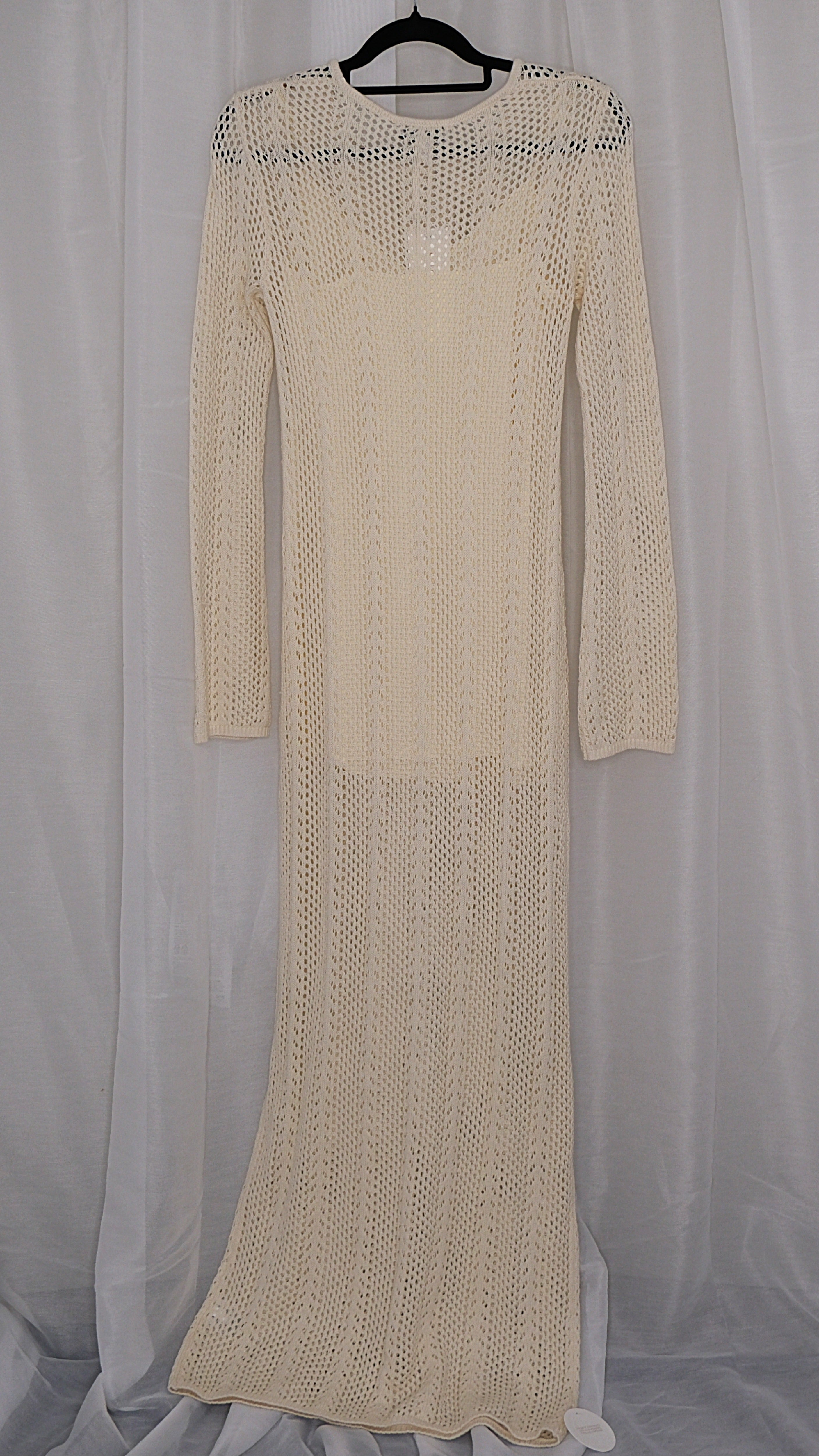 Beige long-sleeve crochet dress on a hanger against a light white background