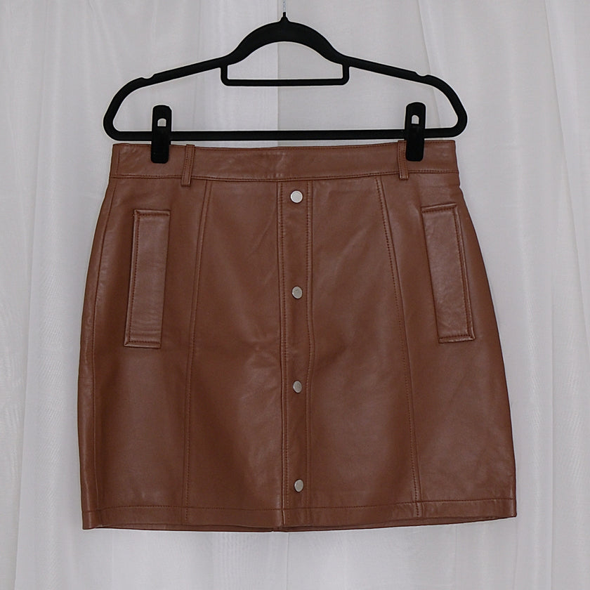 Brown leather skirt on a hanger against a white background