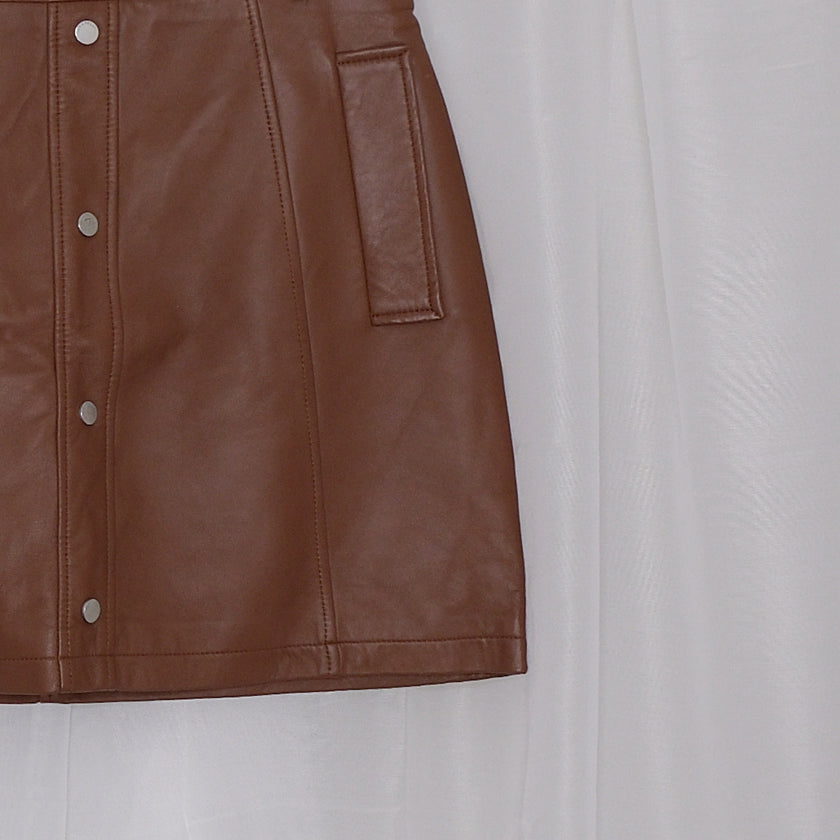 Brown leather skirt on a hanger against a white background