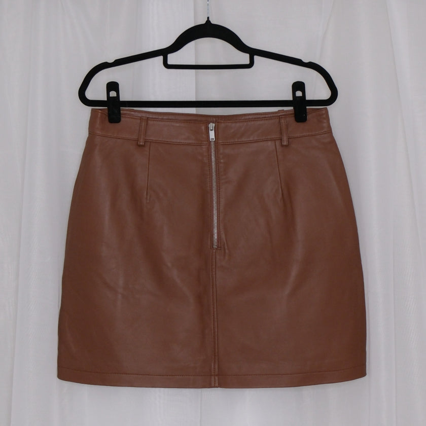 Brown leather skirt on a hanger against a white background