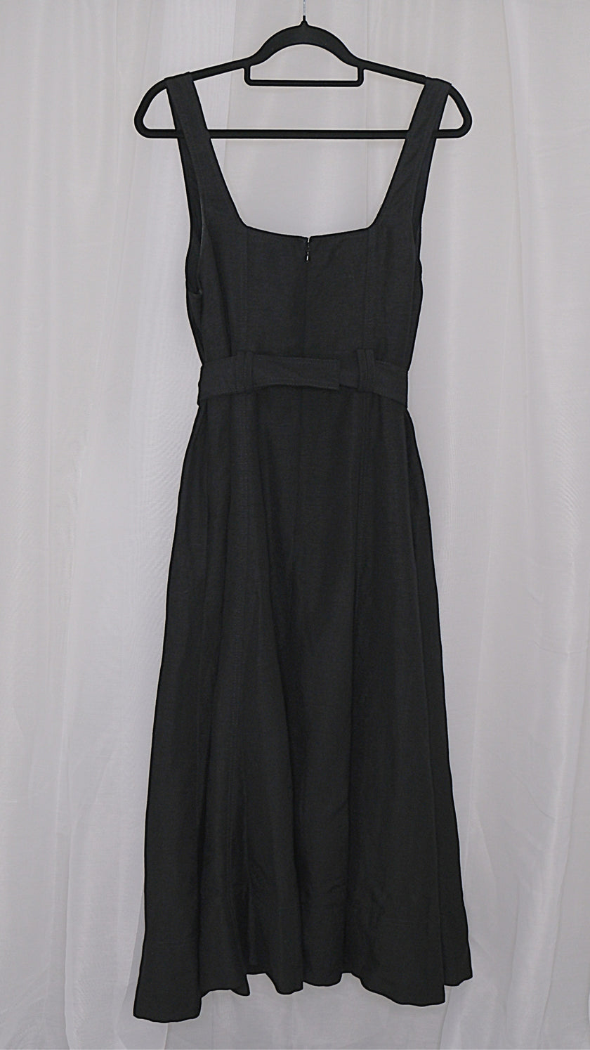 Black dress with gold buttons and belt on a hanger against a light white background