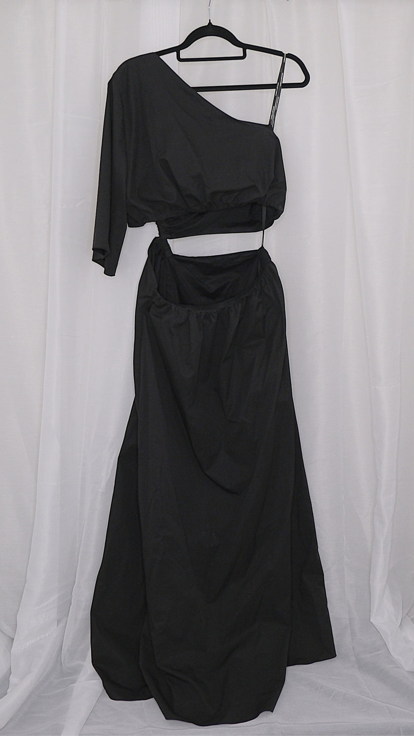 Black asymmetrical dress with cut outs on a hanger against a white background
