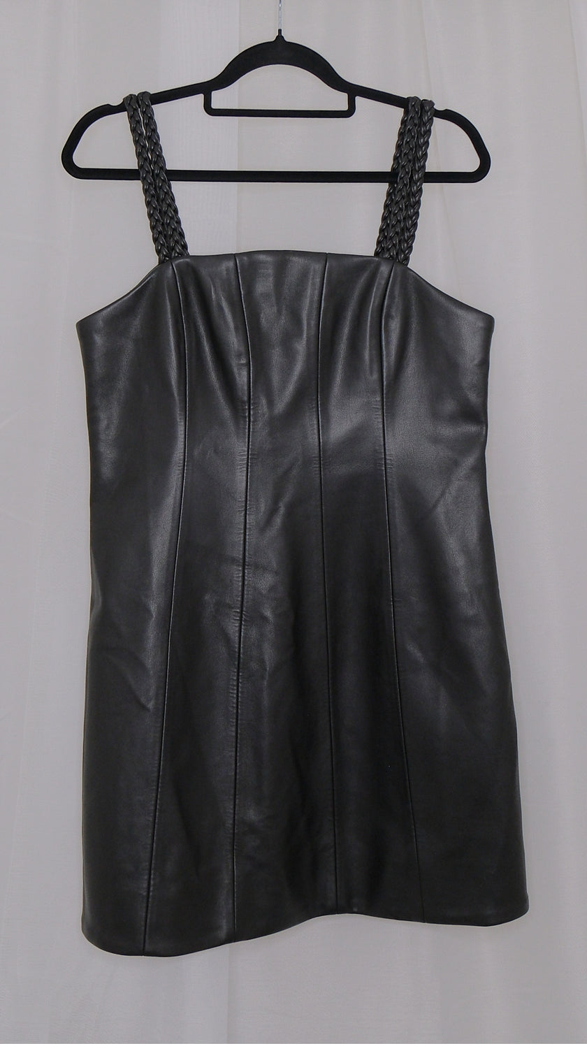 Black leather dress with braided straps on a hanger against a plain background
