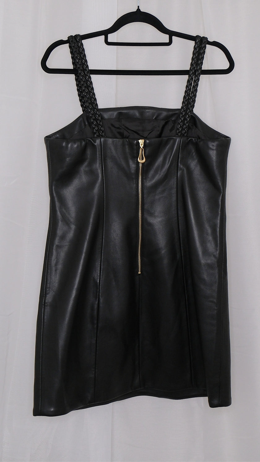 Black leather dress with braided straps on a hanger against a plain background