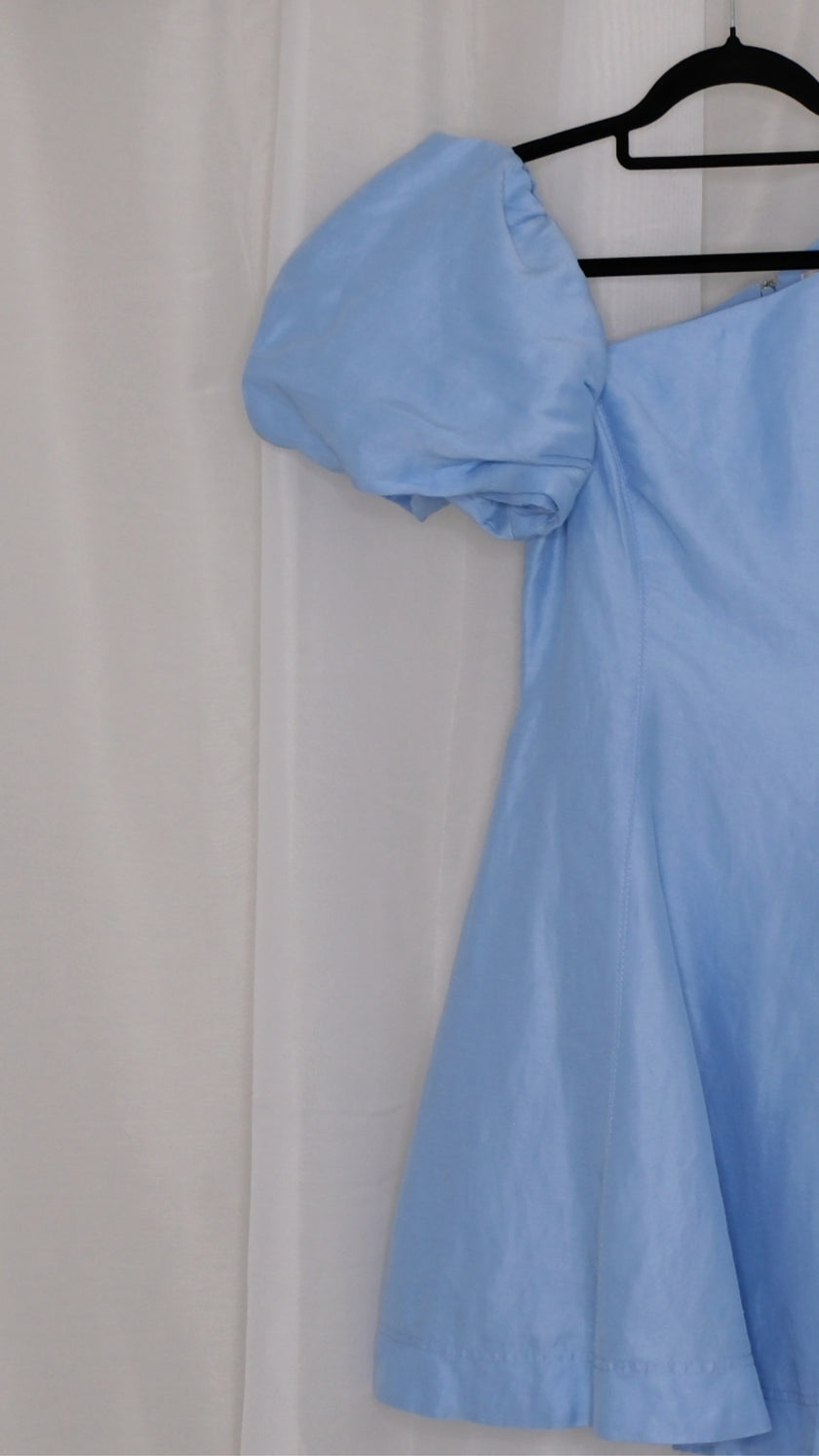 Light blue dress with puff sleeves on a hanger against a white background