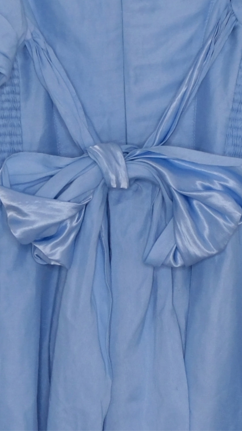 Light blue dress with puff sleeves and bow on a hanger against a white background