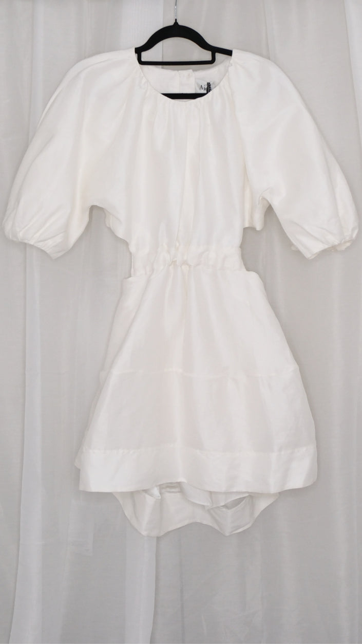 White dress with puff sleeves and tie waist on a hanger against a plain background