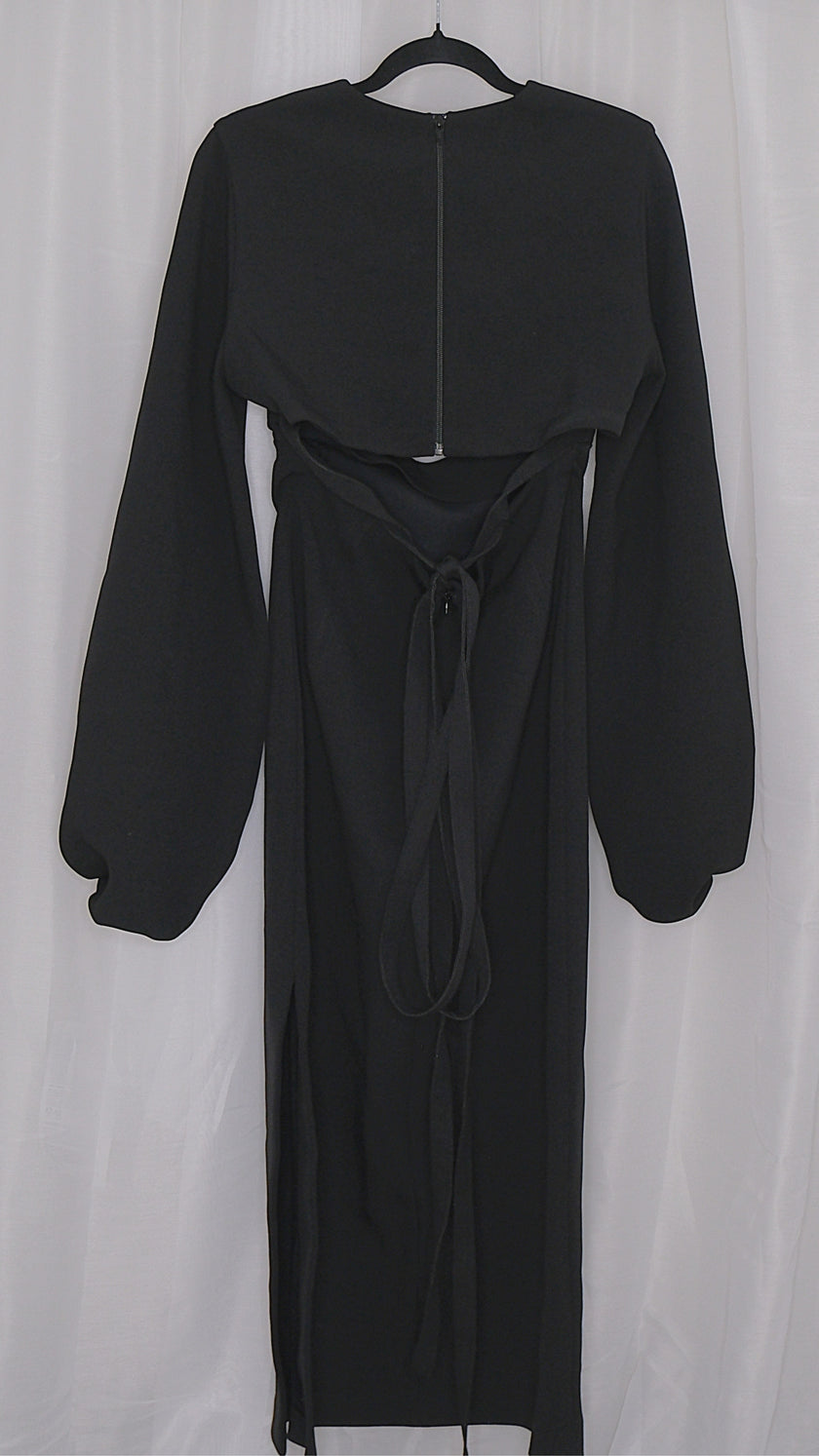 Black dress with long sleeves and cut outs on a hanger against a white background