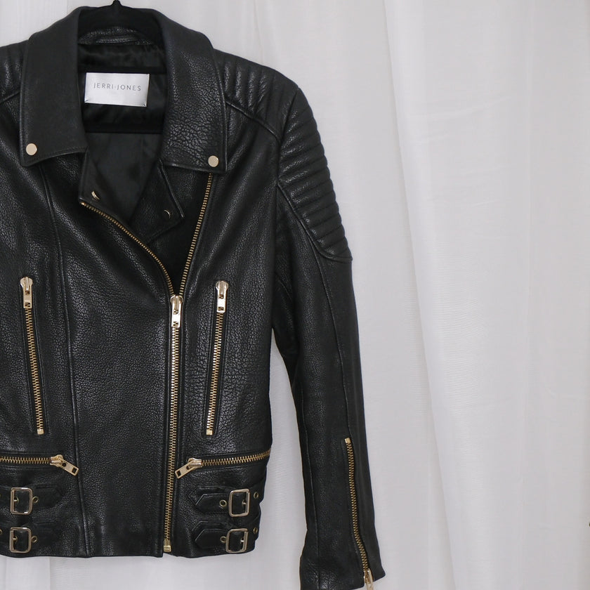 Black leather jacket with gold zippers on a white background