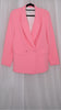 Pink suit with blazer and pants on hangers against a plain background