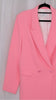 Pink suit with blazer and pants on hangers against a plain background