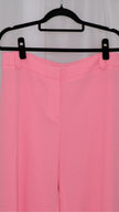 Pink suit with blazer and pants on hangers against a plain background