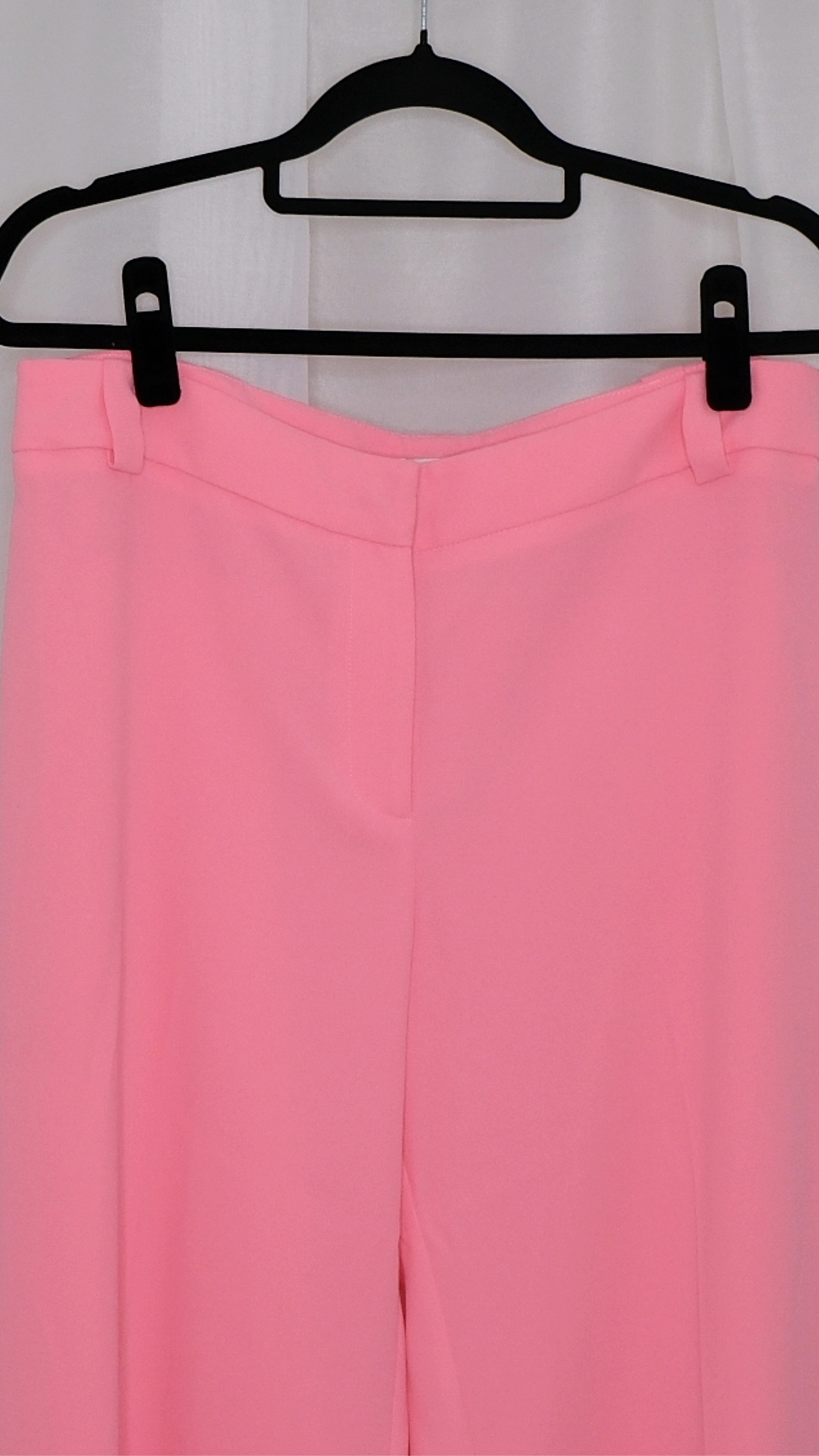 Pink suit with blazer and pants on hangers against a plain background