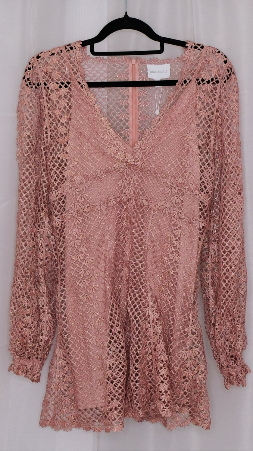 Pink lace dress with slip on a hanger against a white background