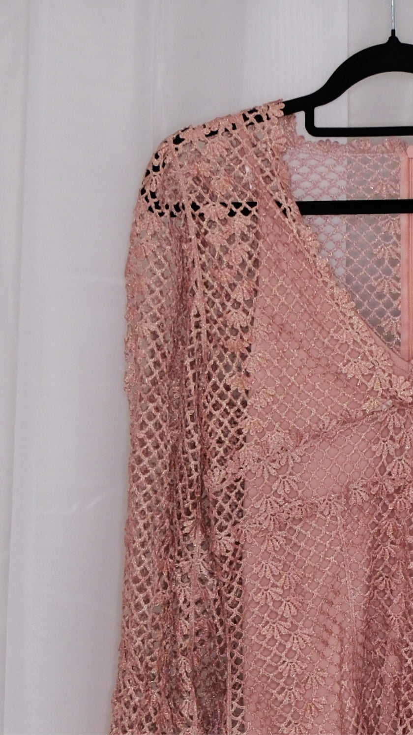 Pink lace dress with slip on a hanger against a white background