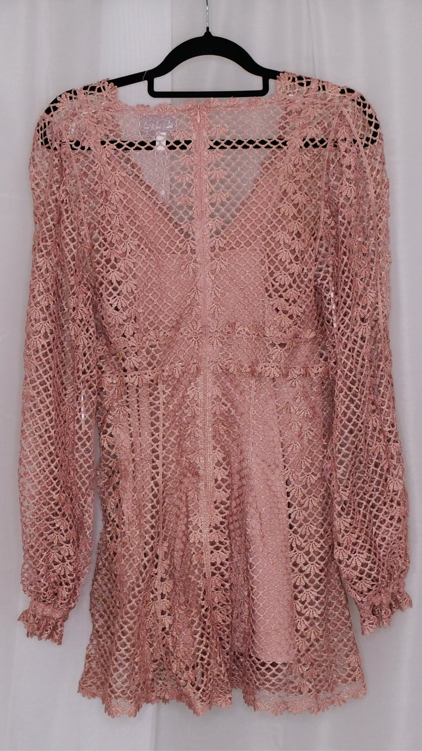 Pink lace dress with slip on a hanger against a white background