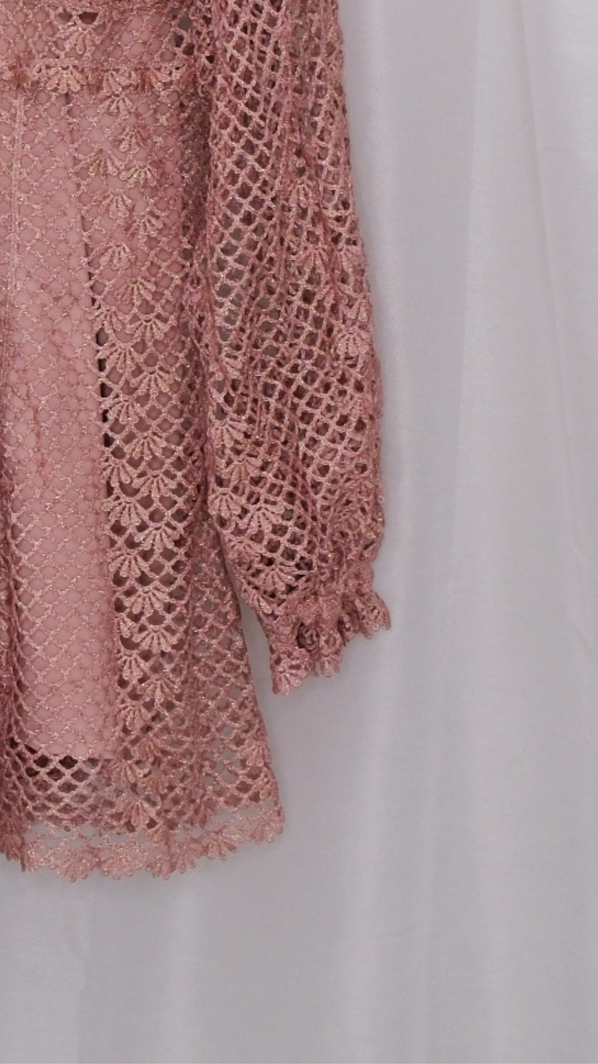 Pink lace dress with slip on a hanger against a white background