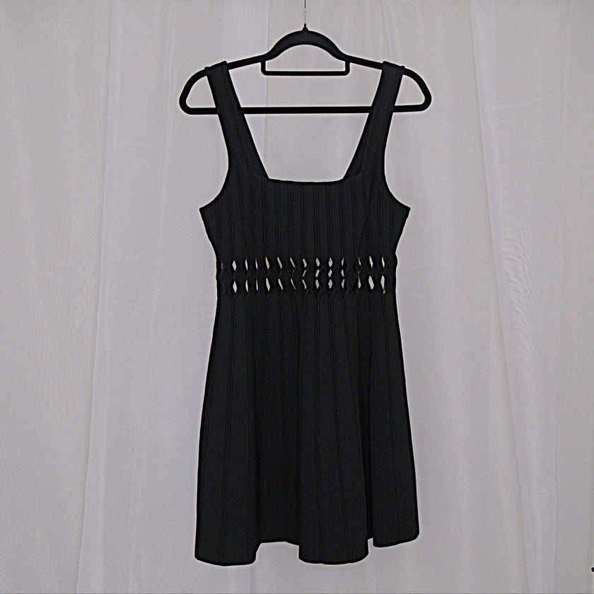 Black dress with cut-out details on a hanger against a white background