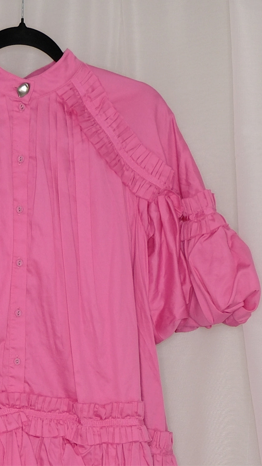 Pink dress with ruffled layers on a hanger against a plain background