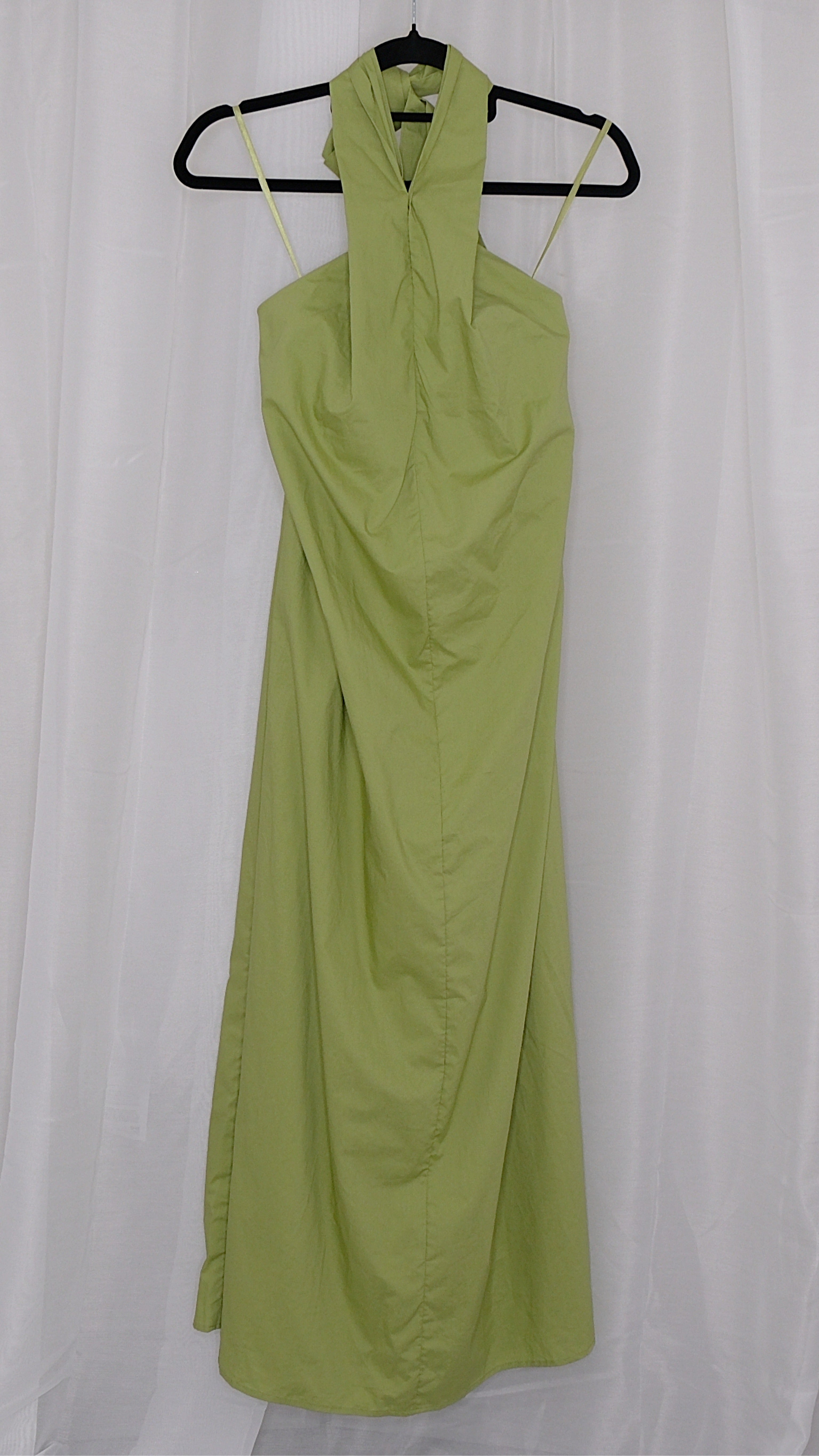 Green halter neck dress on a hanger against a white background