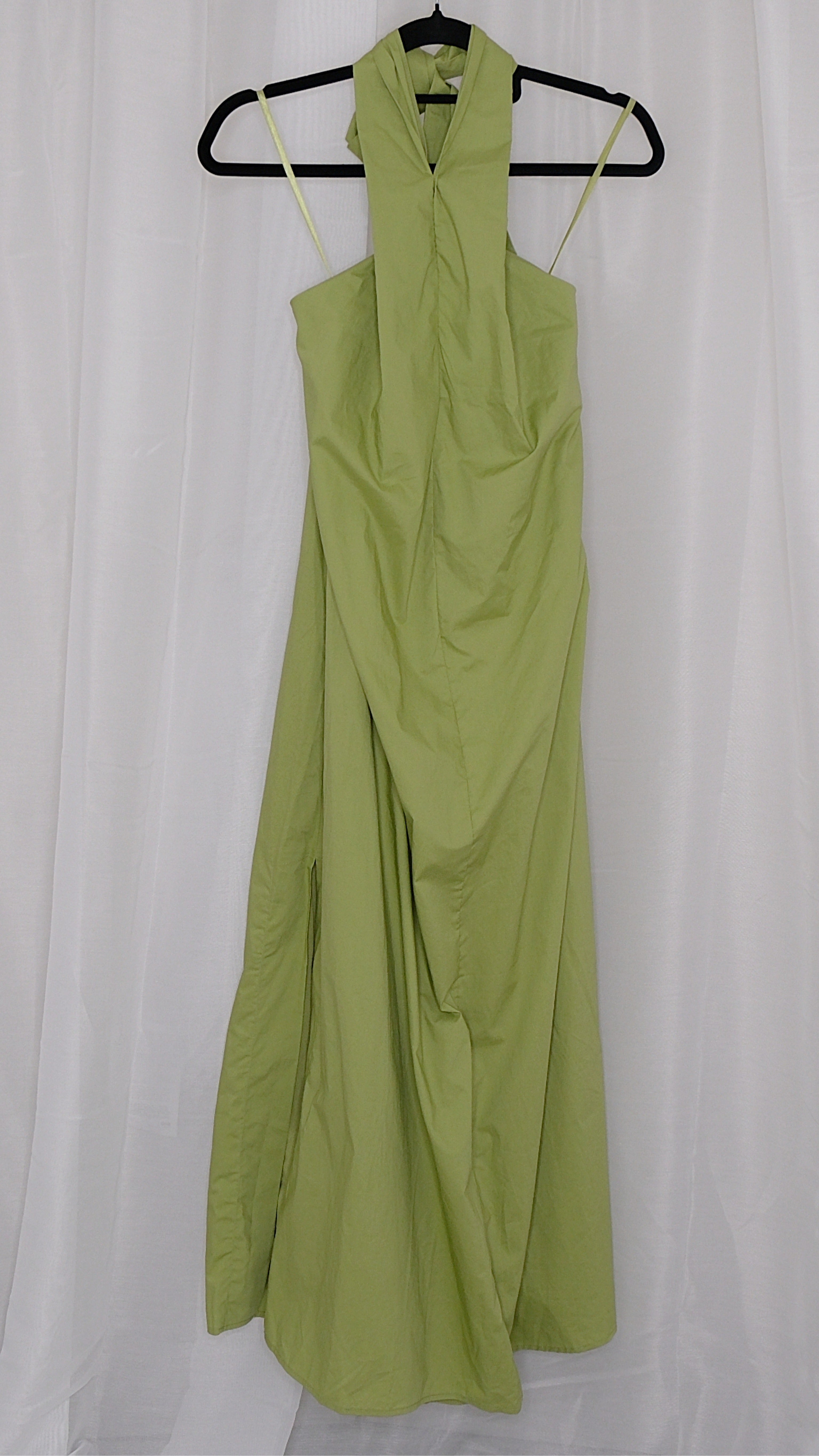 Green halter neck dress on a hanger against a white background
