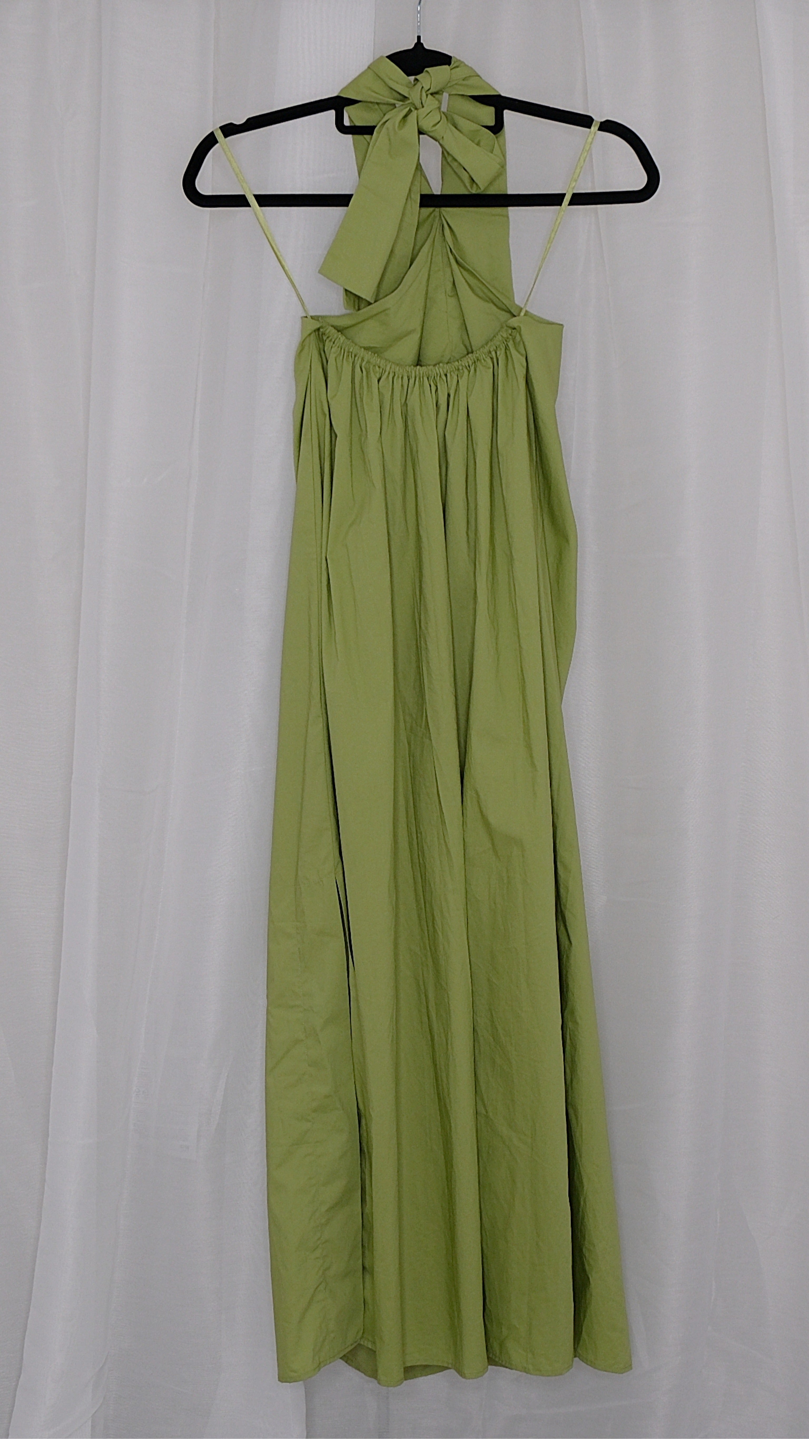 Green halter neck dress on a hanger against a white background