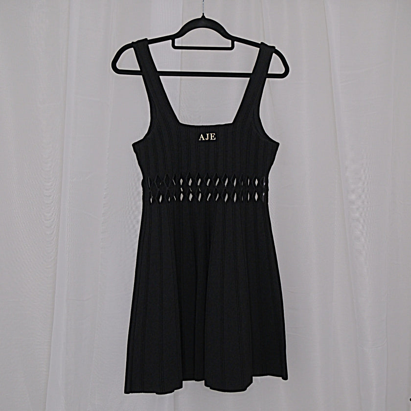 Black dress with cut-out details on a hanger against a white background