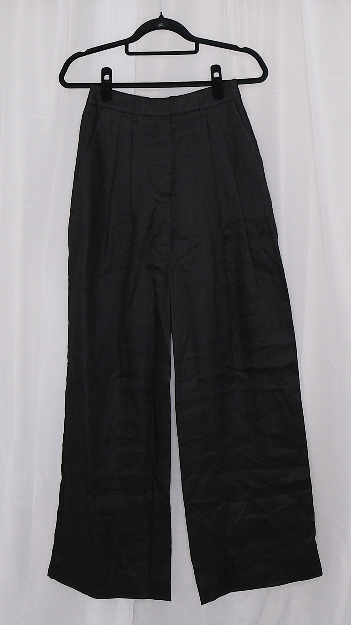 Black wide-leg pants on a hanger against a white background