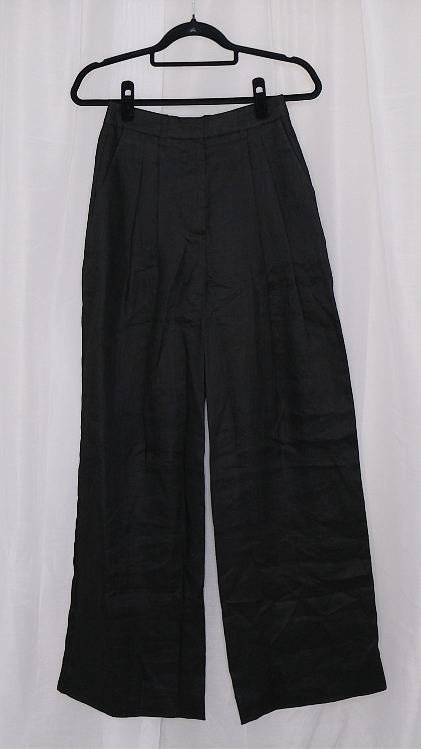 Black wide-leg pants on a hanger against a white background